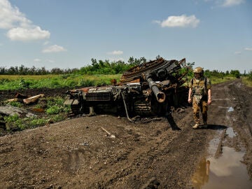 Militar del Ejército de Ucrania inspecciona un tanque ruso destruido en el campo de batalla.