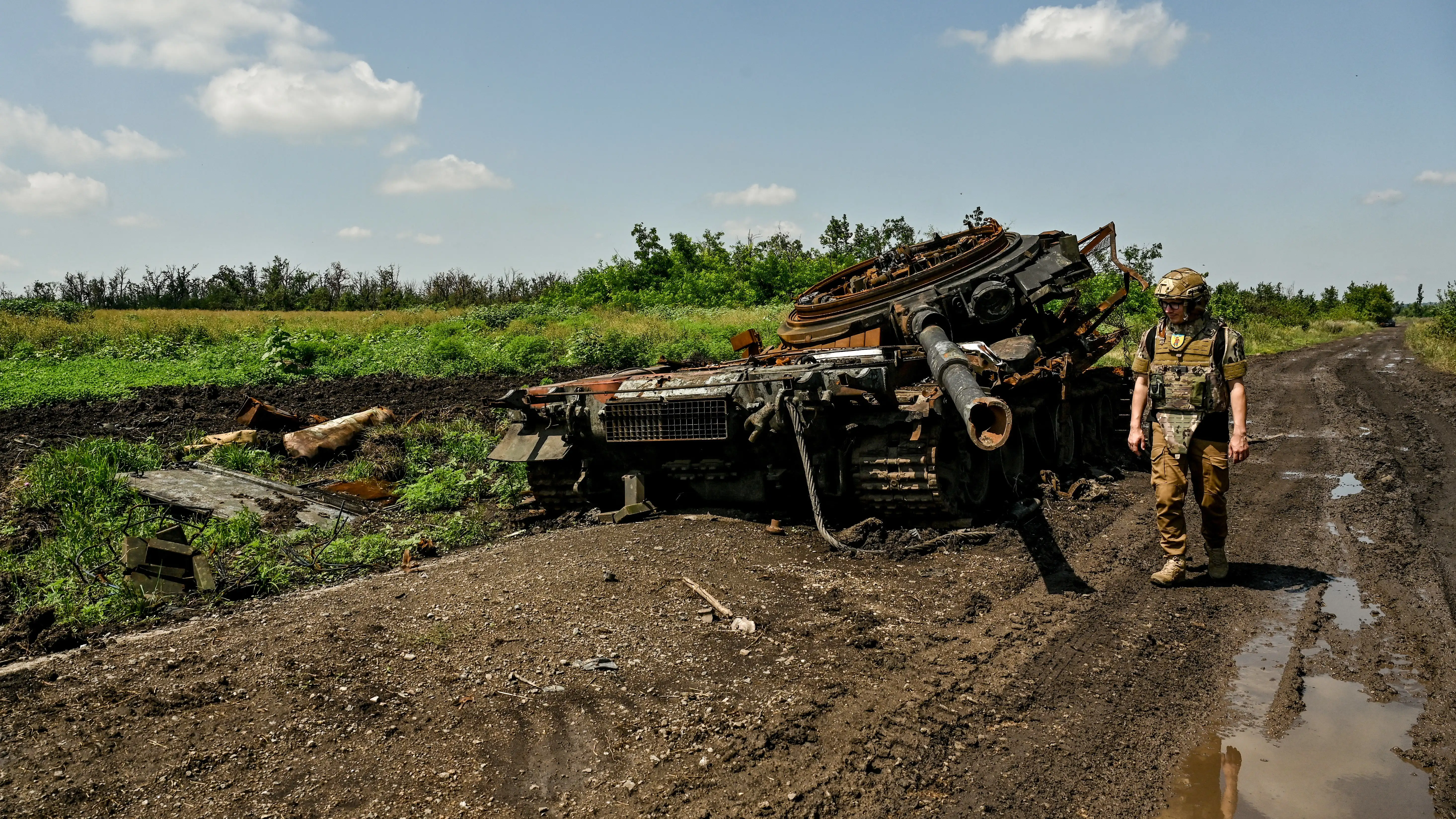 Militar del Ej&eacute;rcito de Ucrania inspecciona un tanque ruso destruido en el campo de batalla.