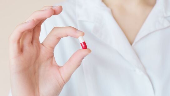 Una mano sostiene una pastilla de medicamento