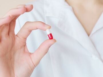 Una mano sostiene una pastilla de medicamento