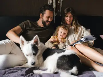 Una familia lee un cuento en la cama Una familia lee un cuento en la cama