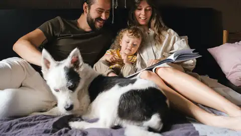 Una familia lee un cuento en la cama Una familia lee un cuento en la cama