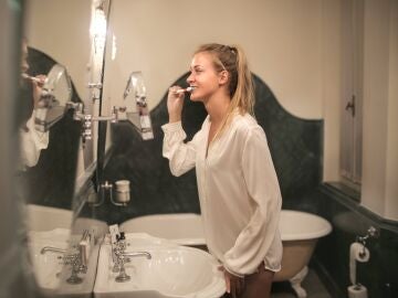 Una mujer se cepilla los dientes frente al espejo