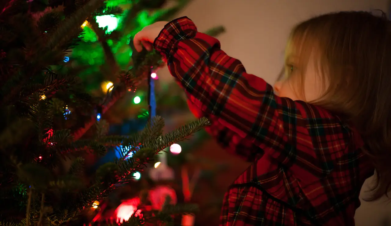 Una niña junto al árbol de Navidad