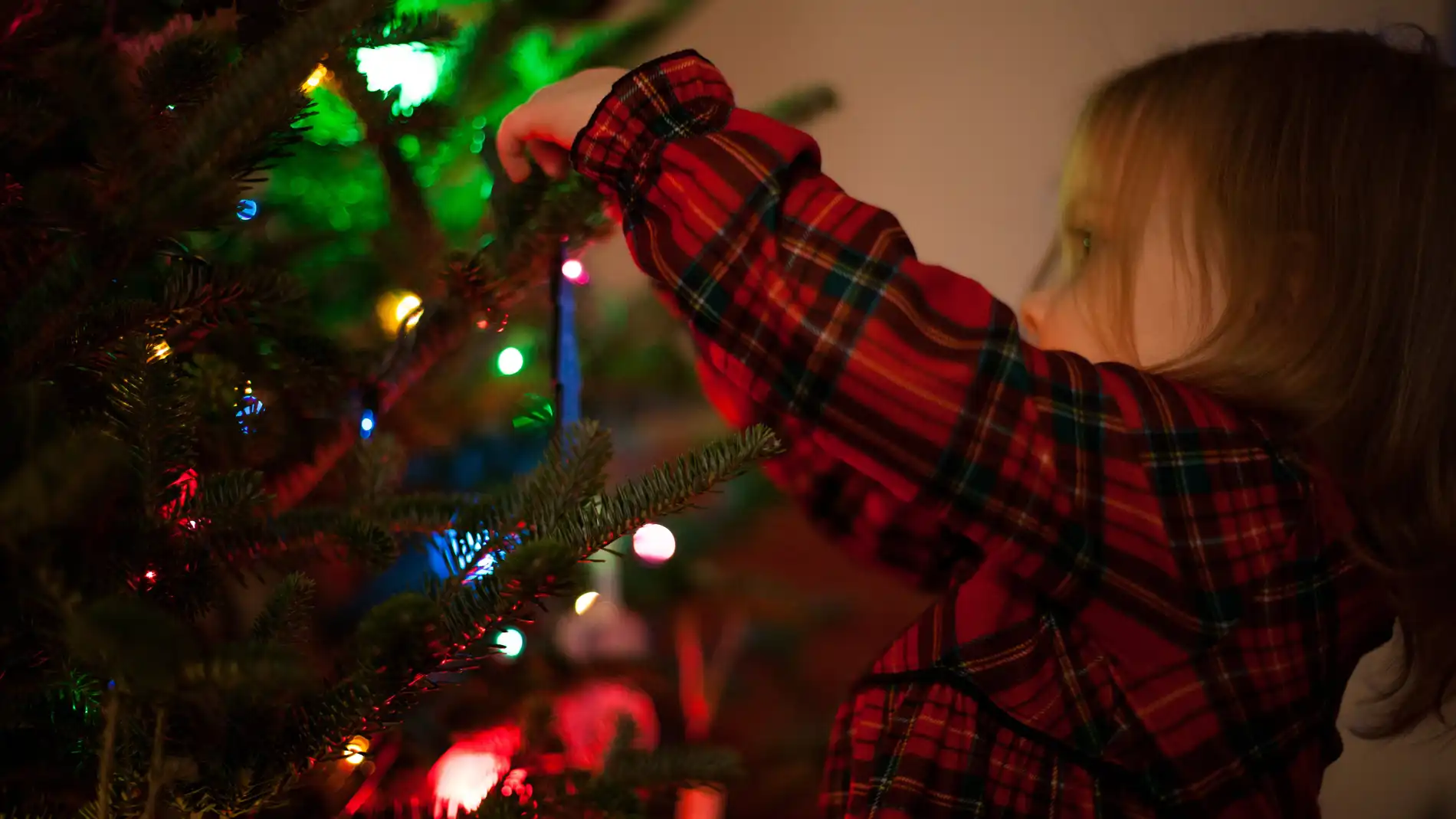 Una niña junto al árbol de Navidad