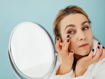 Mujer mirándose la piel del rostro Mujer mirándose la piel del rostro