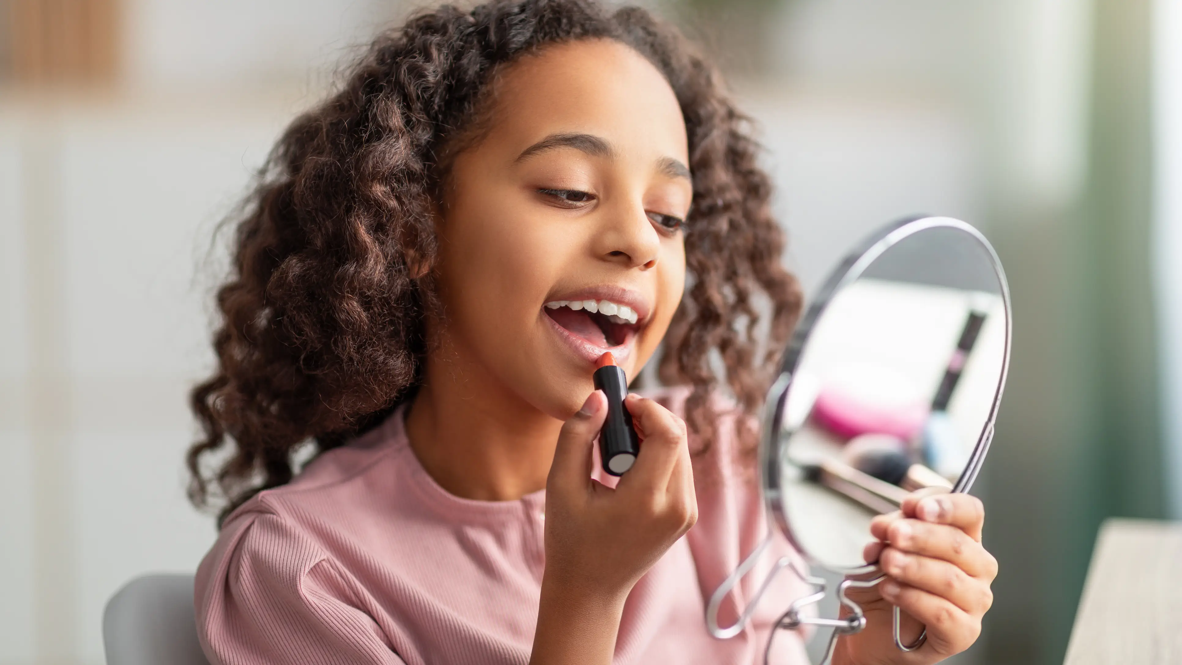 Niña pintándose los labios mientras se mira al espejo Niña pintándose los labios mientras se mira al espejo