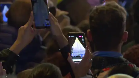 Persona en un evento grabando con su dispositivo