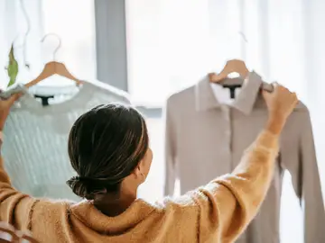 Mujer comparando dos prendas de ropa Mujer comparando dos prendas de ropa