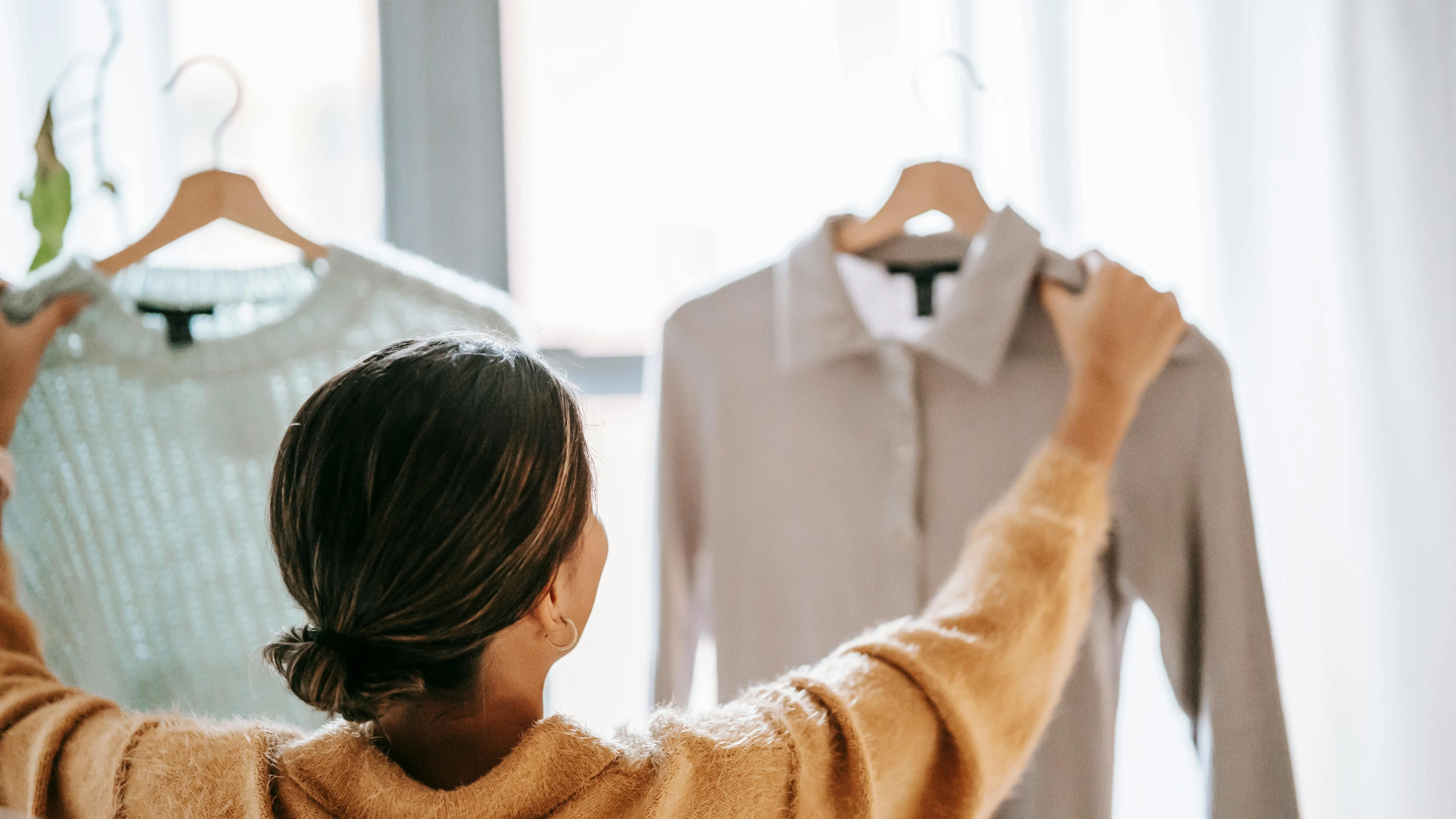 Mujer comparando dos prendas de ropa Mujer comparando dos prendas de ropa