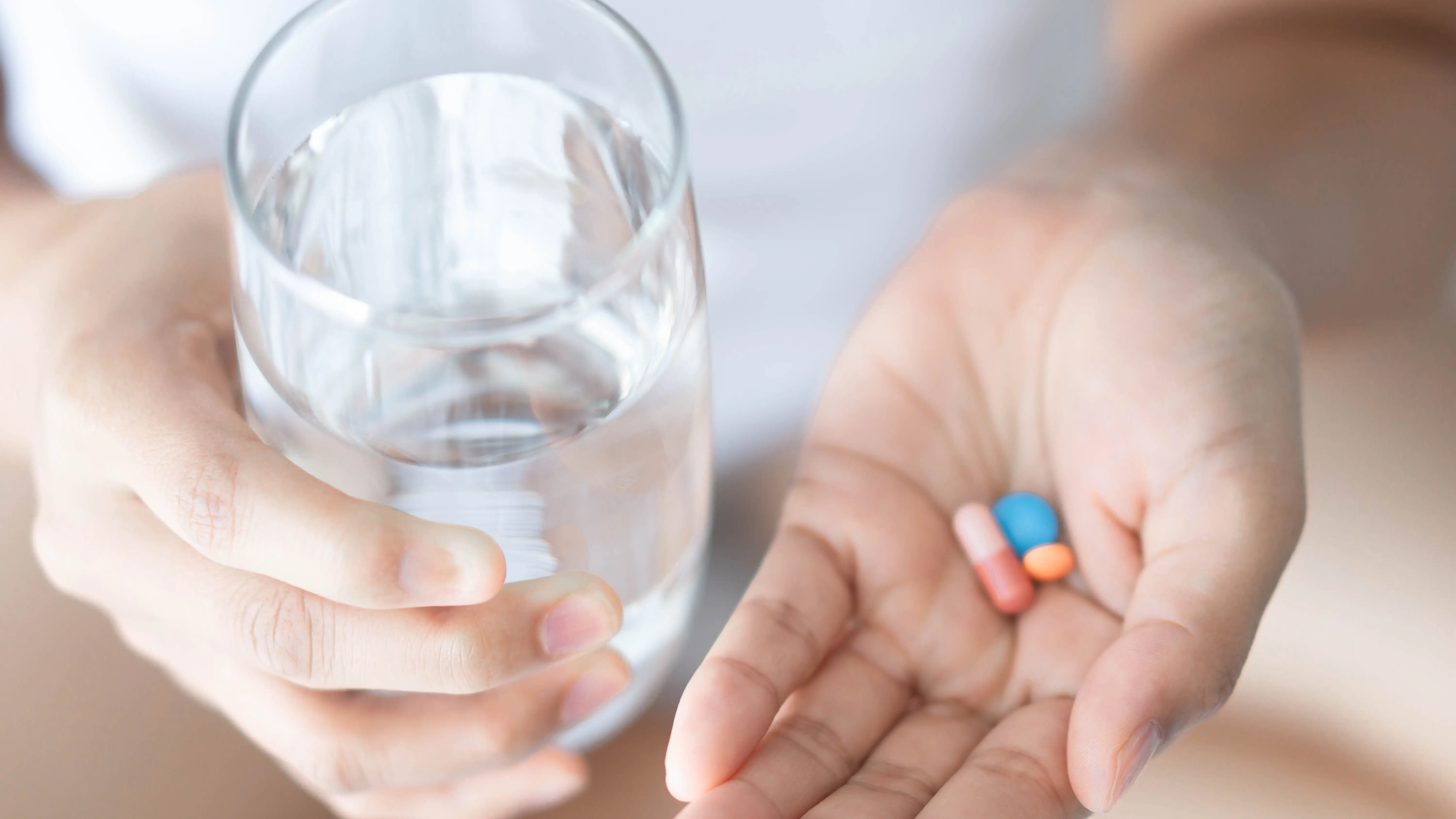 Mujer sosteniendo píldoras y vaso de agua Mujer sosteniendo píldoras y vaso de agua