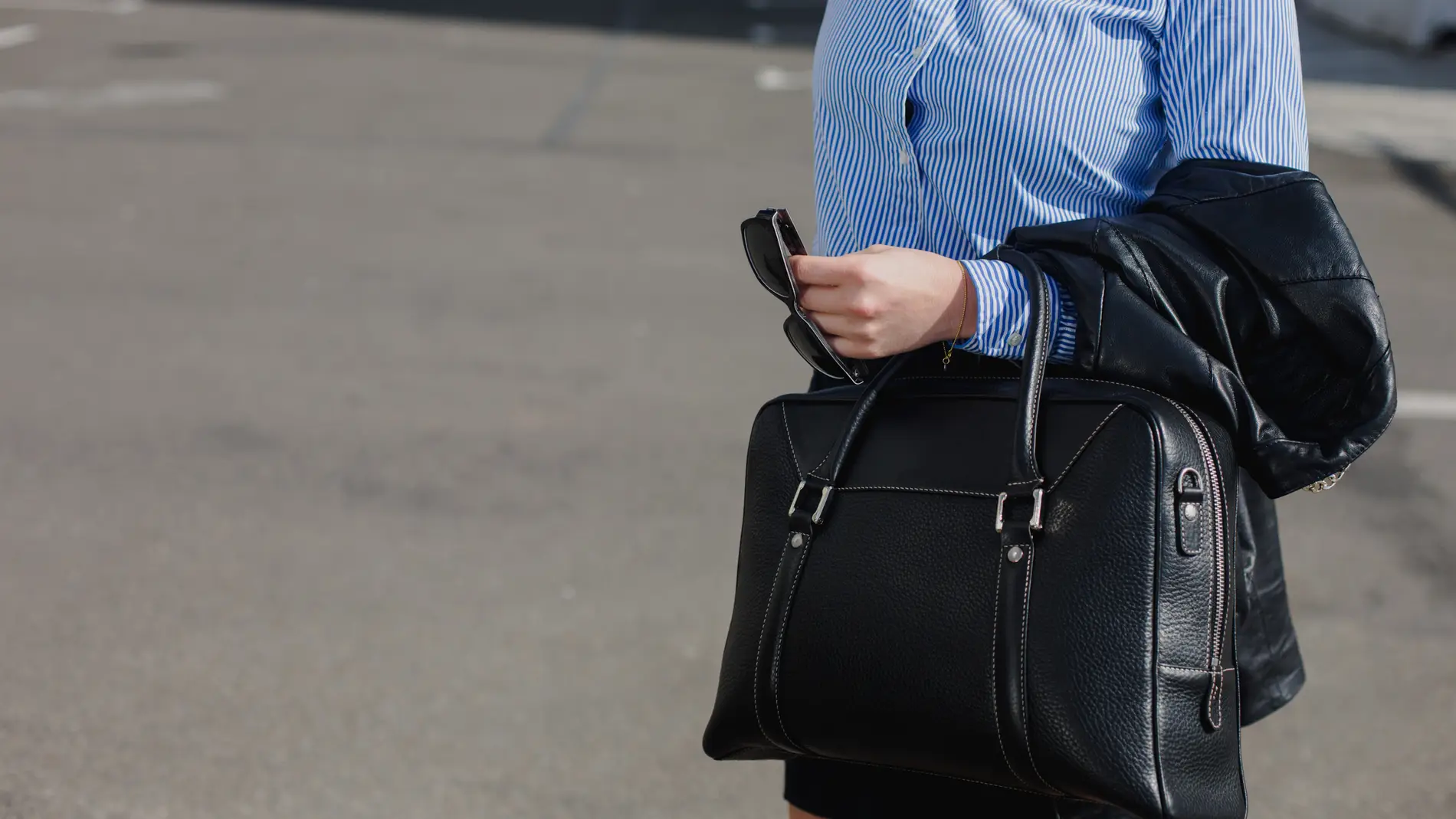 Mujer llevando un bolso grande de piel negro