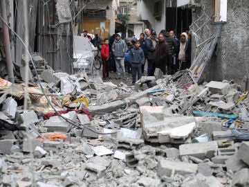 Palestinos entre los restos de un bombardeo israelí