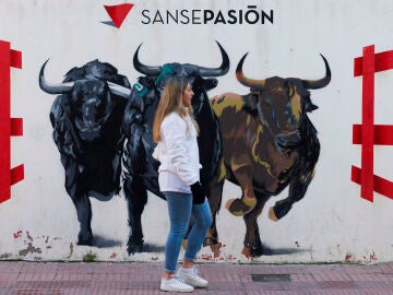 Una mujer pasa delante de un mural durante los "Encierros Blancos" en San Sebastián de los Reyes, Madrid, este sábado