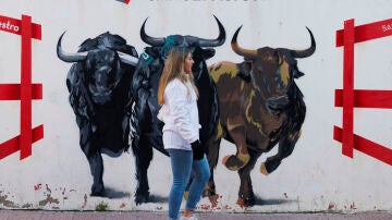 Una mujer pasa delante de un mural durante los "Encierros Blancos" en San Sebastián de los Reyes, Madrid, este sábado