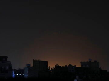 Vista general este sábado, 3 de febrero, del resplandor producto de ataques aéreos, detrás de un conjunto de edificios, en Saná