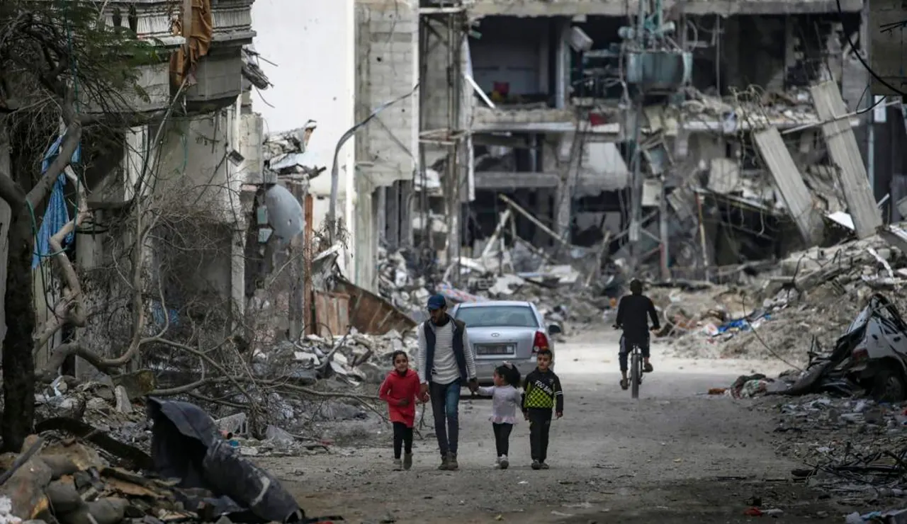 Una familia palestina camina entre la destrucción en el campo de refugiados de Al Bureije (Gaza)