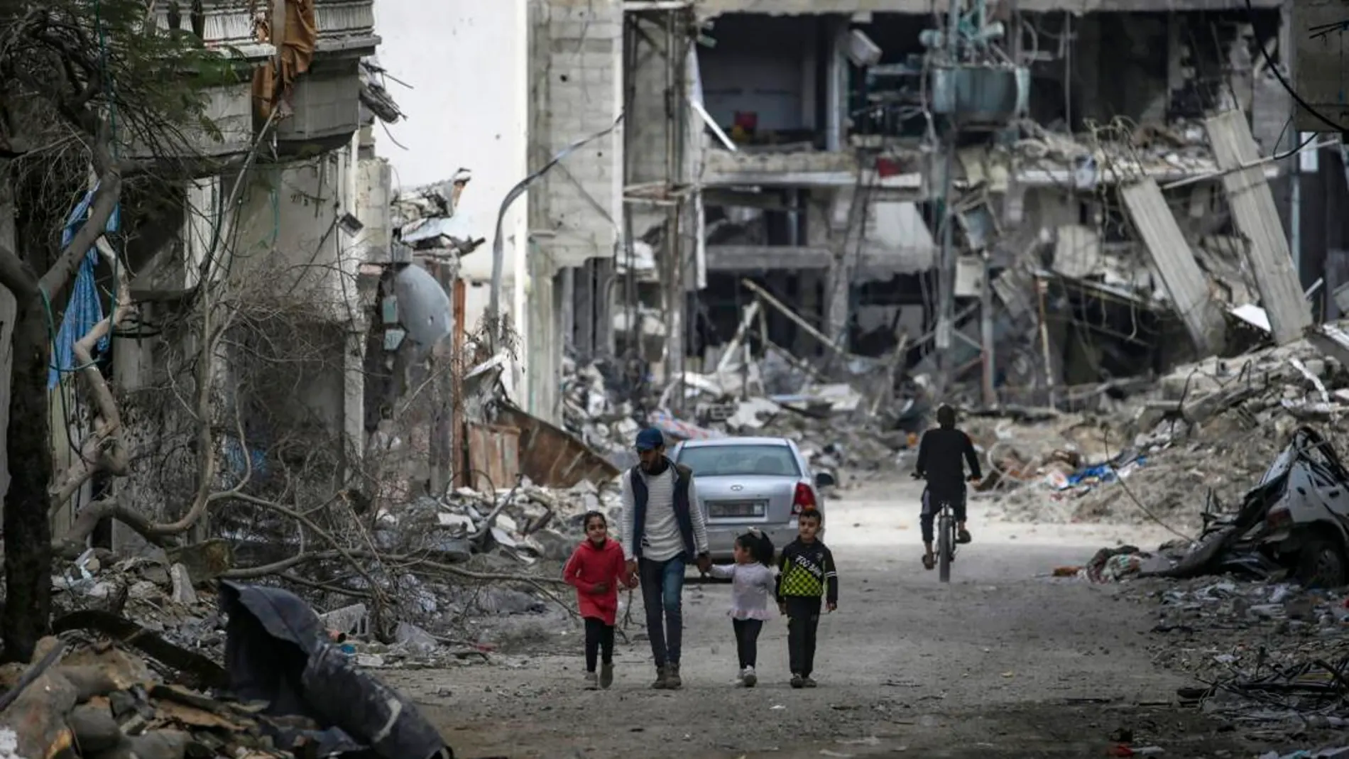 Una familia palestina camina entre la destrucción en el campo de refugiados de Al Bureije (Gaza)