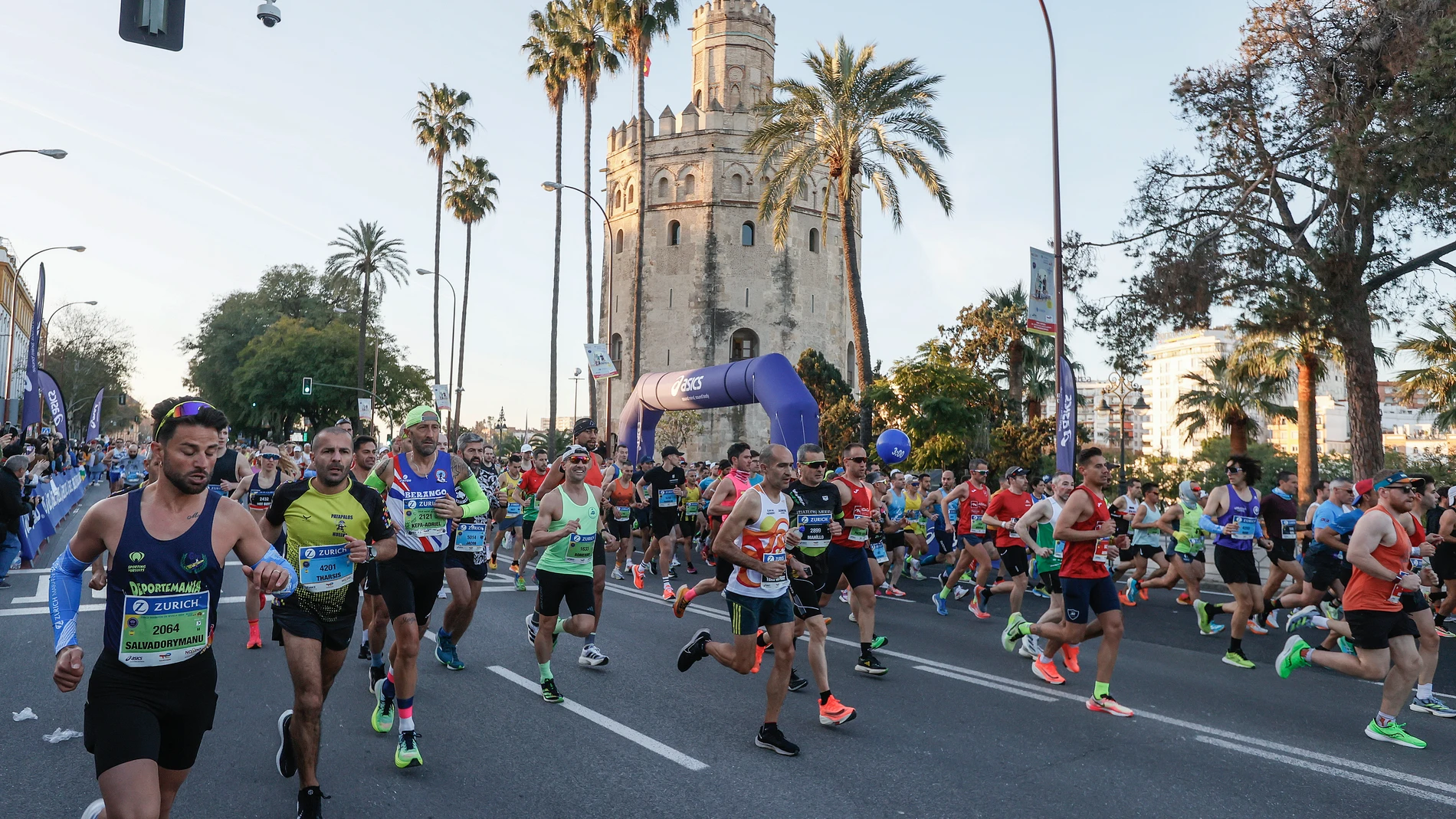 Corredores pasan por la Torre del Oro durante la Maratón de Sevilla