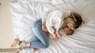 Una mujer da el pecho a su bebé tumbada en la cama