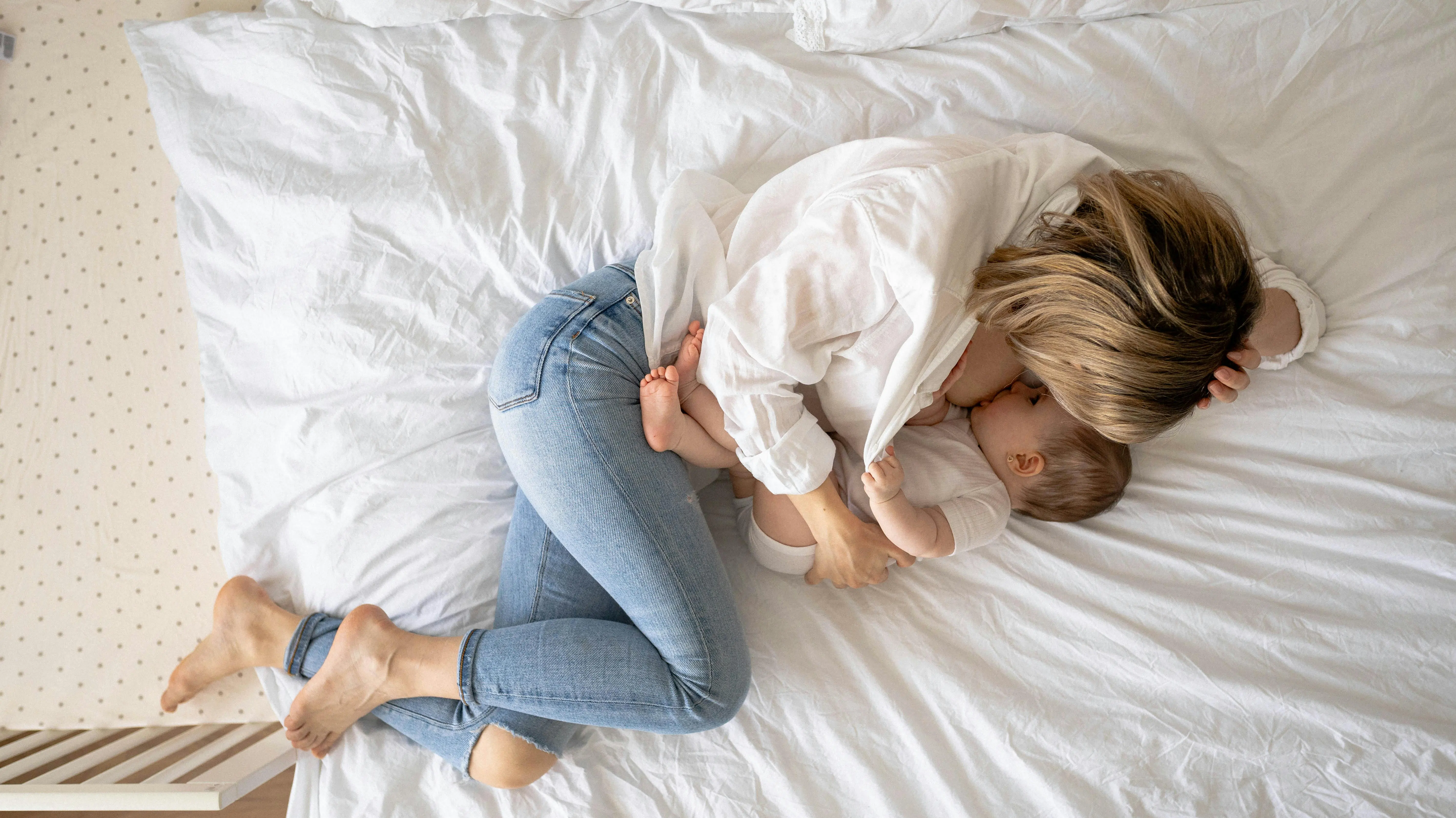 Una mujer da el pecho a su beb&eacute; tumbada en la cama