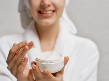 Una mujer echándose crema Una mujer echándose crema