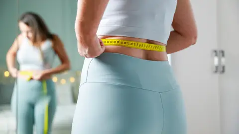 Una mujer se mide el perímetro de la cintura Una mujer se mide el perímetro de la cintura
