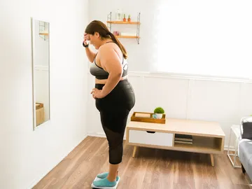 Una mujer se pesa en una báscula de su casa Una mujer se pesa en una báscula de su casa