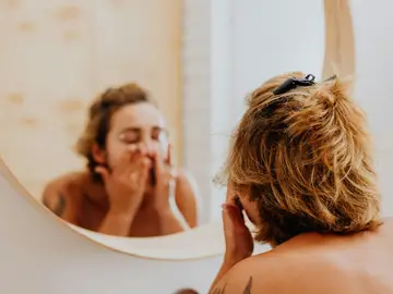 Mujer poniéndose crema facial Mujer poniéndose crema facial