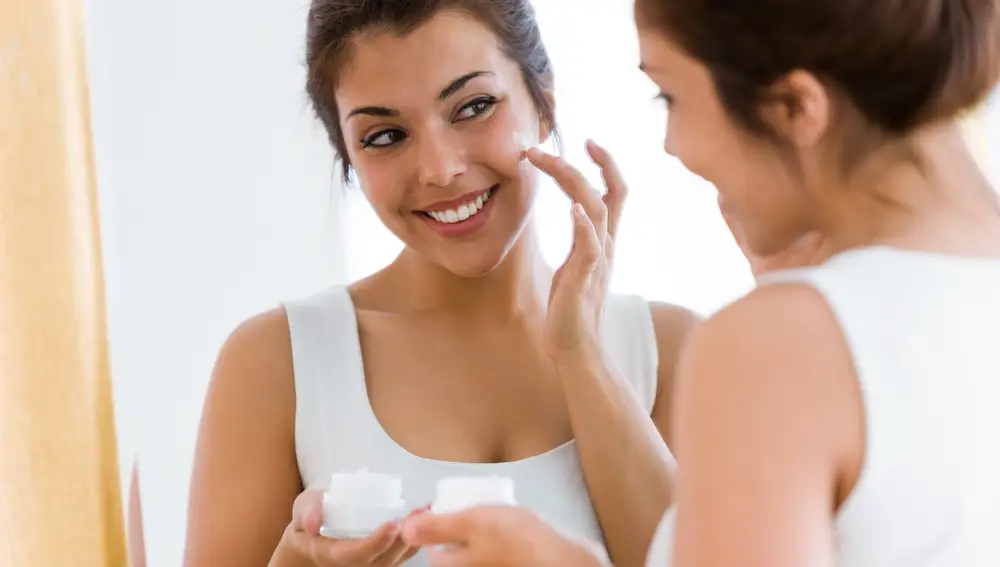 Mujer aplicándose crema en la cara Mujer aplicándose crema en la cara