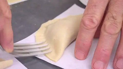 Dóblalas y ciérralas presionando los bordes con un tenedor. Dóblalas y ciérralas presionando los bordes con un tenedor.