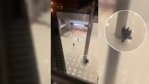 Dos personas se ocultan tras una columna durante el tiroteo. Dos personas se ocultan tras una columna durante el tiroteo.