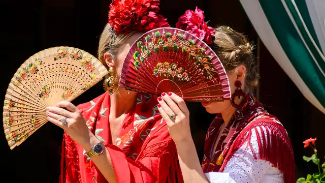 Dos mujeres vestidas de flamenca evitan mirar a los borrachos en el Real de la Feria de Abril de Sevilla Dos mujeres vestidas de flamenca evitan mirar a los borrachos en el Real de la Feria de Abril de Sevilla