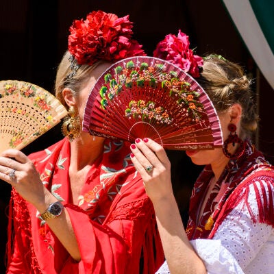 Dos mujeres vestidas de flamenca evitan mirar a los borrachos en el Real de la Feria de Abril de Sevilla Dos mujeres vestidas de flamenca evitan mirar a los borrachos en el Real de la Feria de Abril de Sevilla