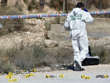 Un agente de la científica de la Guardia Civil clasifica pruebas en la zona donde se encontró el cadáver