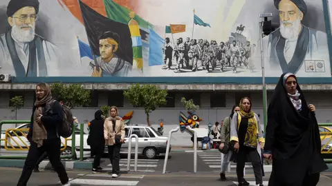 Varias mujeres pasean con el velo por delante de un mural del líder supremo iraní Varias mujeres pasean con el velo por delante de un mural del líder supremo iraní