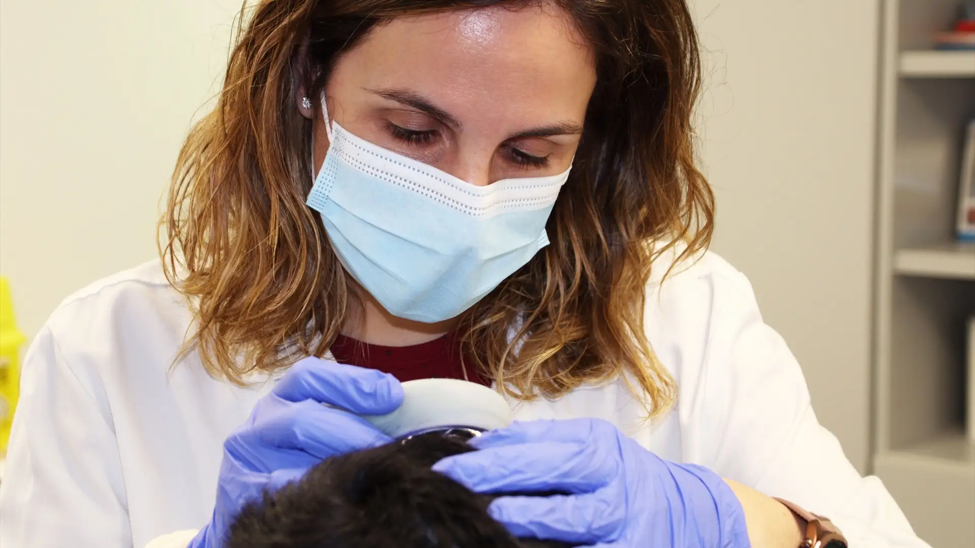 Una dermatóloga revisa el cuero cabelludo Una dermatóloga revisa el cuero cabelludo
