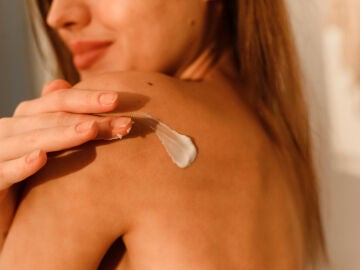 Una mujer se aplica crema en la espalda.