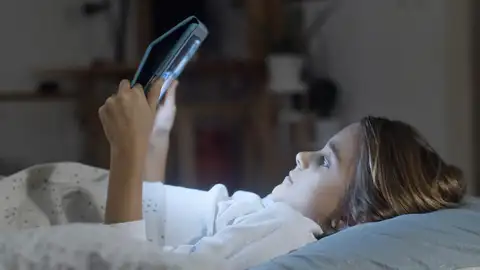 Una niña con una tablet en la cama. Una niña con una tablet en la cama.
