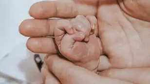 Persona sosteniendo la mano de un bebé