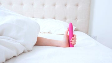 Mujer sujetando un juguete sexual en la cama
