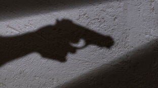Sombra de una mano sujetando una pistola