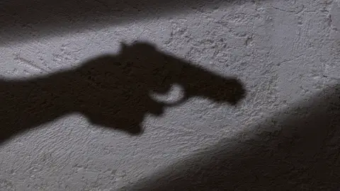Sombra de una mano sujetando una pistola Sombra de una mano sujetando una pistola