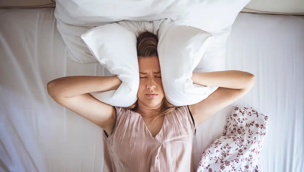 Persona tapándose las orejas con una almohada