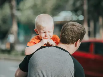 Un niño llora en brazos de su padre Un niño llora en brazos de su padre