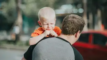 Un niño llora en brazos de su padre