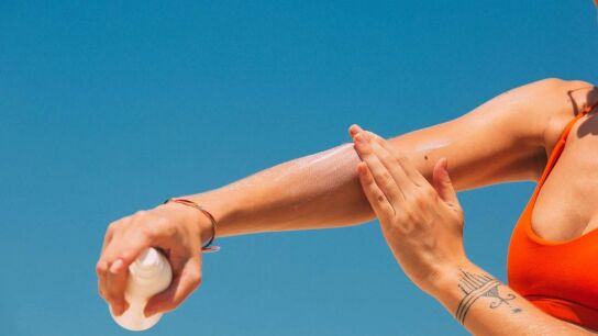 Una mujer aplic&aacute;ndose crema solar