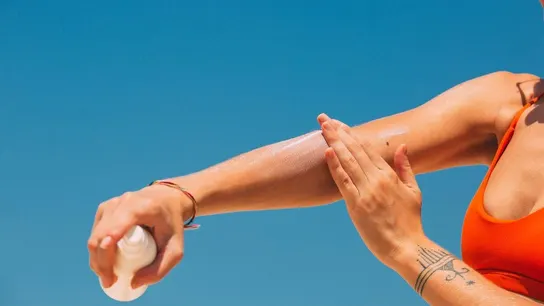 Una mujer aplicándose crema solar Una mujer aplicándose crema solar