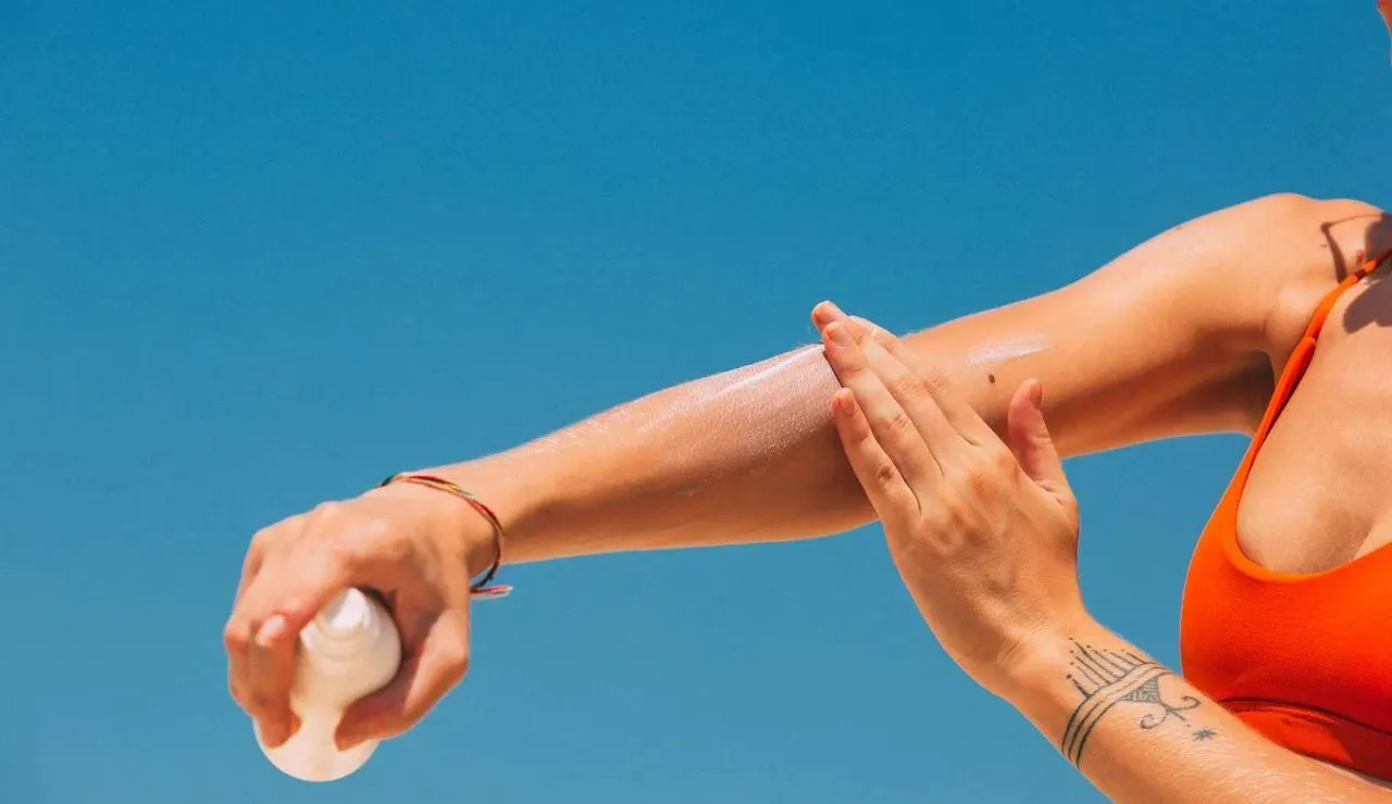 Una mujer aplicándose crema solar