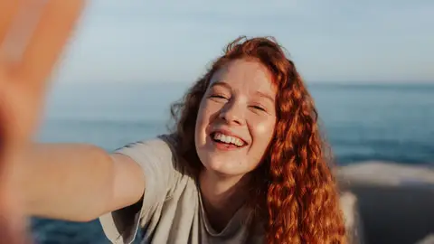 Una chica peliroja sonríe mientras se hace un selfie Una chica peliroja sonríe mientras se hace un selfie